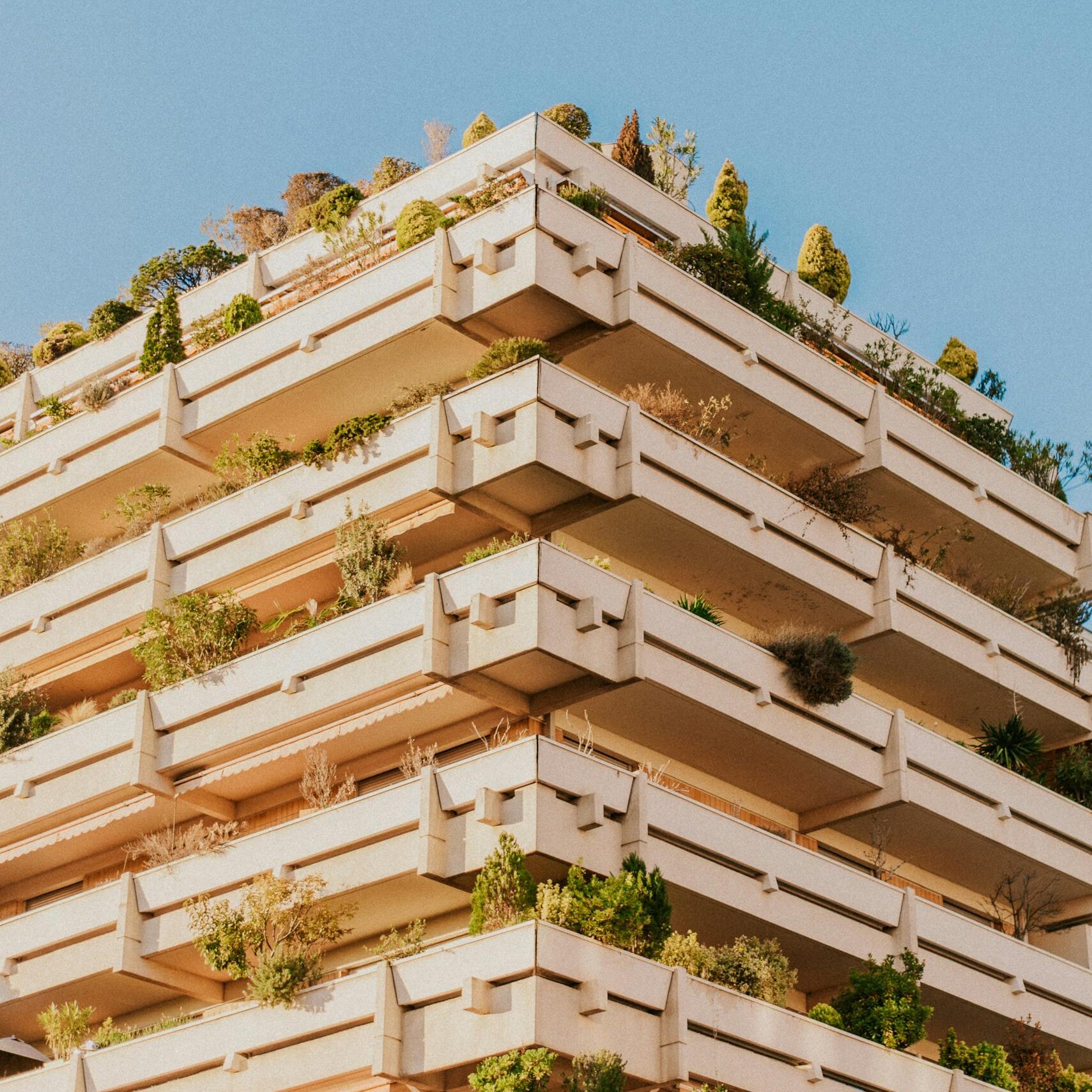 A modern building in Toulouse showcases green architecture with lush balconies filled with plants.